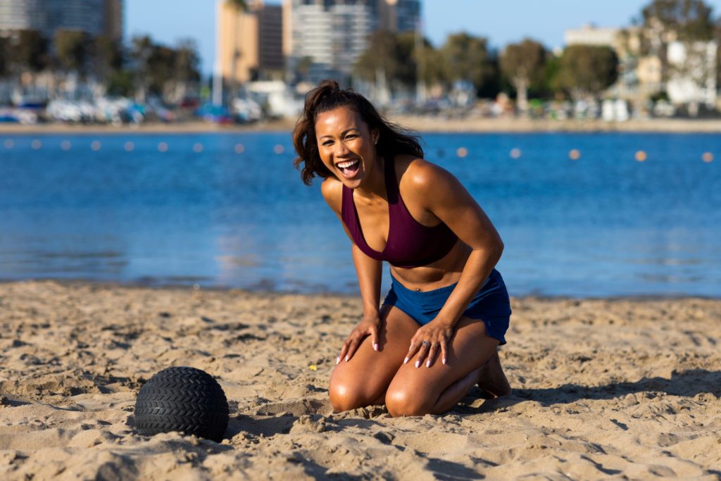 200618_074_Maricris_Lapaix-scaled0 Maricris kneeling on the beach next to a medicine ball